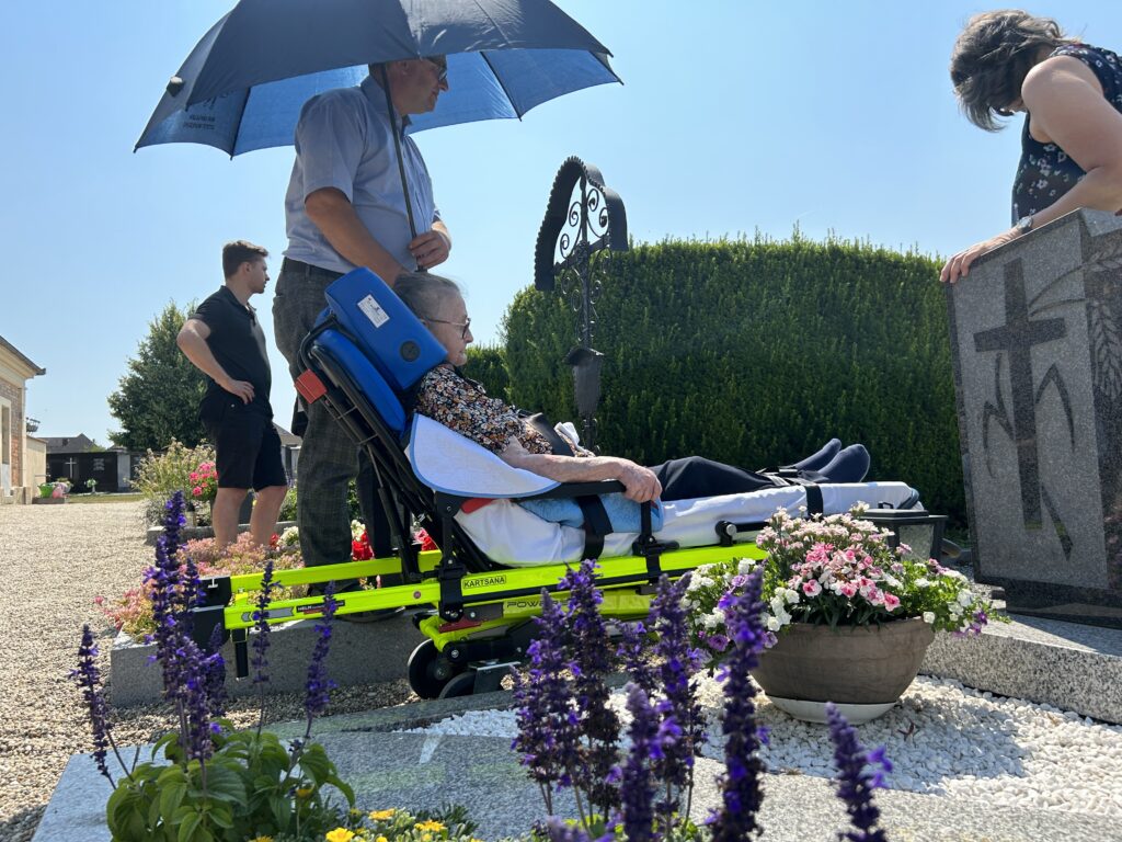 Mann hält Schirm Friedhof Fahrgast Grab liegt auf Trage Sonne Hitze Temperaturen